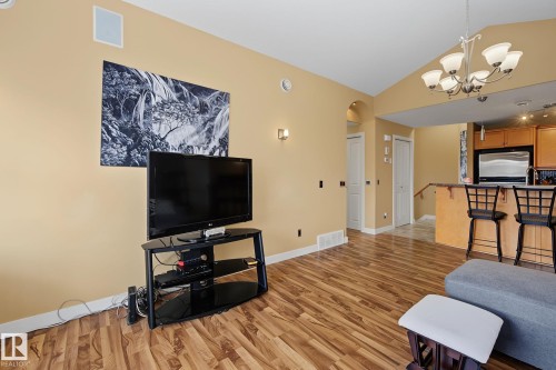 Open-concept living space featuring wood-finish flooring, vaulted ceilings, and a built-in speaker - 30 2565 Hanna Crescent, Edmonton, AB 
