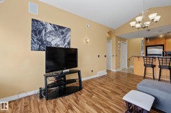 Open-concept living space featuring wood-finish flooring, vaulted ceilings, and a built-in speaker - 