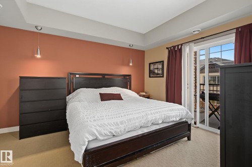 Bedroom with tray ceiling, pendant lighting, and direct access to an exterior balcony - 30 2565 Hanna Crescent, Edmonton, AB 