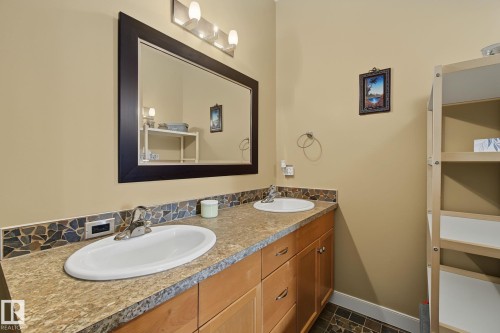 Dual vanity featuring oval undermount sinks, stone-finish countertops, and a mosaic tile backsplash - 30 2565 Hanna Crescent, Edmonton, AB 