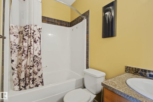 Bathroom featuring a bathtub with an integrated shower, a toilet, and a vanity with a light-colored countertop - 30 2565 Hanna Crescent, Edmonton, AB 
