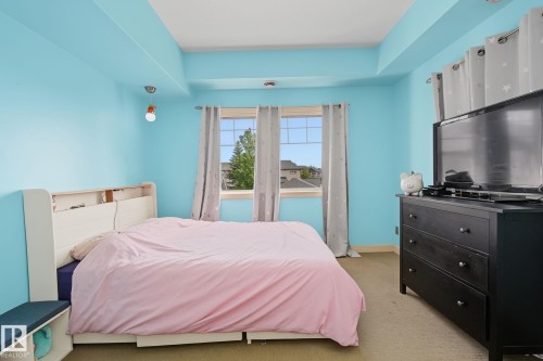 Room featuring light blue walls, tray ceiling detail, a window with grid panes, and neutral carpeting - 30 2565 Hanna Crescent, Edmonton, AB 