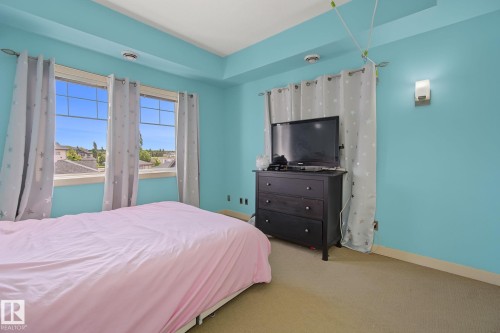 Room featuring two large windows, a tray ceiling, and wall-mounted lighting - 30 2565 Hanna Crescent, Edmonton, AB 