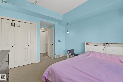 Carpeted room featuring a double bifold door closet, light blue wall paint, white trim, and a white interior door with black hardware - 30 2565 Hanna Crescent, Edmonton, AB 