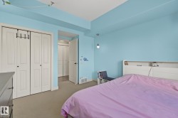 Carpeted room featuring a double bifold door closet, light blue wall paint, white trim, and a white interior door with black hardware - 