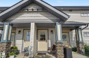 Exterior entry with stone-clad pillars, a covered porch, horizontal siding, decorative gable shingles, and an exterior wall light - 30 2565 Hanna Crescent, Edmonton, AB 