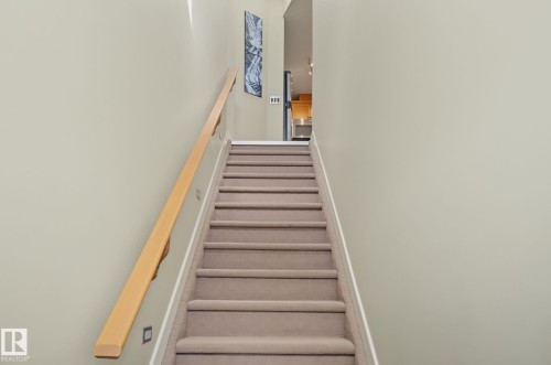 Carpeted staircase with light wood-finish handrail and integrated wall lighting - 30 2565 Hanna Crescent, Edmonton, AB 