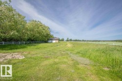 Expansive green field bordered by a white fence - 