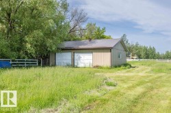 Detached garage structure featuring two white overhead doors and a metal roof - 