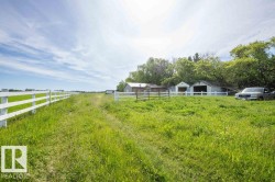 Expansive green acreage featuring a long white post-and-rail fence - 