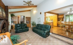 Vaulted ceilings with exposed wood beams define this spacious living area, featuring a brick fireplace with an arched opening and built-in shelving - 