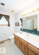 Bathroom featuring a wood-finish vanity with an integrated sink, a large mirror, and a corner shower with glass enclosure - 