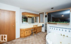 Built-in vanity with countertop, integrated mirror, and overhead lighting - 