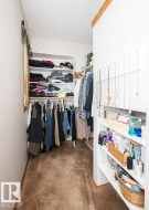 Walk-in closet featuring extensive built-in shelving, multiple hanging rods, and a window for natural light - 