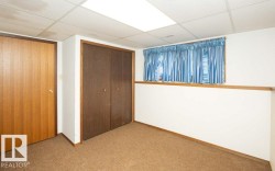 Carpeted room featuring a drop ceiling with recessed lighting, a window with blue curtains, and a light wood-finish door with a dark wood-finish bi-fold closet - 