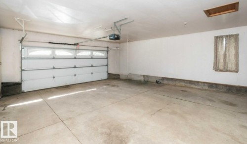 Spacious garage featuring a concrete floor, an overhead door with upper window panels, and an automatic garage door opener - 26530 Twp Rd 590, Rural Westlock County, AB - Indoor Photo Showing Garage