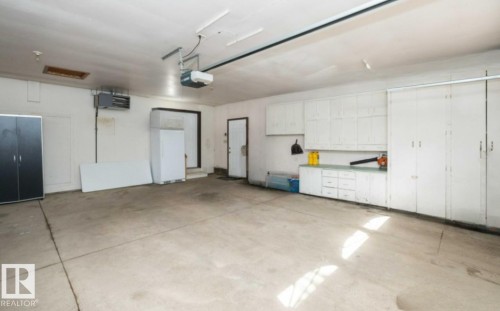 Spacious garage with a concrete floor, built-in white cabinetry, and overhead storage - 26530 Twp Rd 590, Rural Westlock County, AB - Indoor Photo Showing Garage