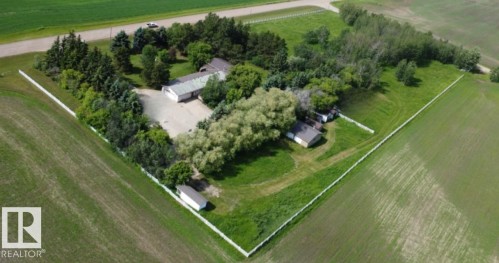 Expansive property featuring multiple structures, mature trees, a white perimeter fence, paved driveways, and surrounded by cultivated green fields - 26530 Twp Rd 590, Rural Westlock County, AB -  With View