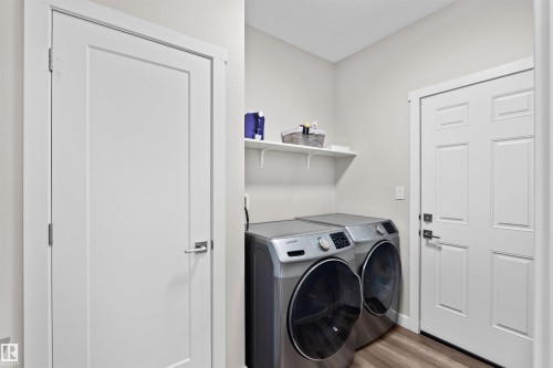 Utility area featuring a floating shelf, wood-finish flooring, white trim, and two white panel doors - 4673 Alwood Way, Edmonton, AB 