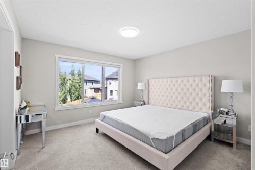 Carpeted room featuring a large window, neutral wall paint, and a ceiling-mounted light fixture - 4673 Alwood Way, Edmonton, AB 