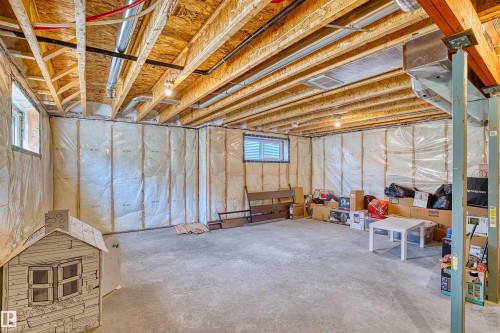 Unfinished basement with exposed ceiling joists and ductwork, featuring concrete flooring, insulated walls, and two visible windows - 4673 Alwood Way, Edmonton, AB 