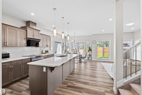Open-concept kitchen with a large central island, light cabinetry, and stainless steel appliances - 4673 Alwood Way, Edmonton, AB 