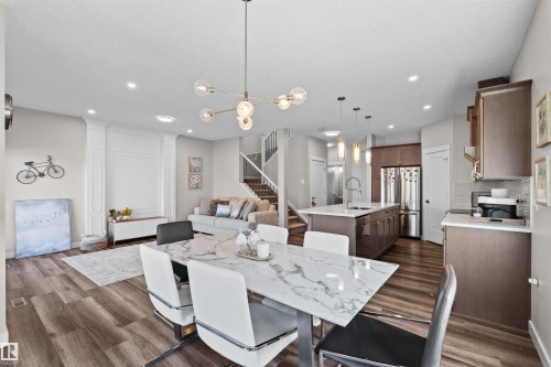 Open-concept living space with wood-finish flooring, a contemporary dining chandelier, and recessed lighting - 4673 Alwood Way, Edmonton, AB 