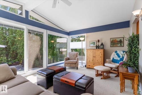 Vaulted ceiling sunroom featuring multiple large windows, a sliding glass door, white trim, and a ceiling fan - 14309 101 Avenue, Edmonton, AB 