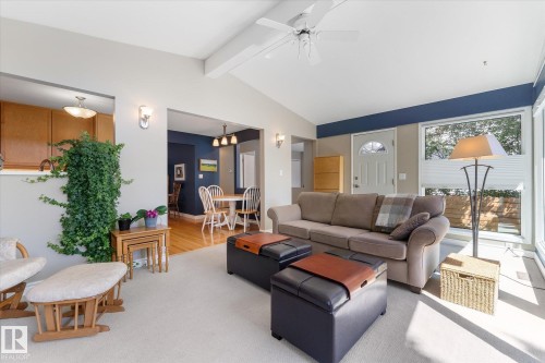 Bright living area featuring a vaulted ceiling with exposed beam, a ceiling fan, and large windows with pleated blinds - 14309 101 Avenue, Edmonton, AB 
