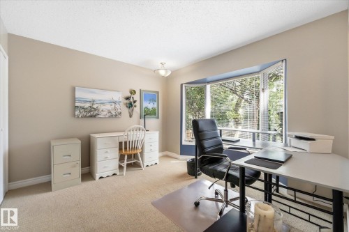 Carpeted room featuring a prominent bay window, neutral wall paint, and a semi-flush ceiling light fixture - 14309 101 Avenue, Edmonton, AB 