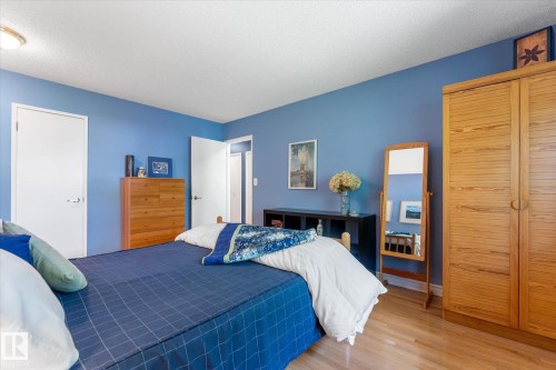 Bedroom featuring light wood-finish flooring, blue painted walls, and a ceiling-mounted light fixture - 14309 101 Avenue, Edmonton, AB 