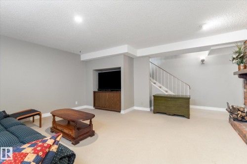 Spacious lower-level living area with light-colored carpeting, recessed lighting, and a built-in media niche with wood-finish cabinetry - 14309 101 Avenue, Edmonton, AB 