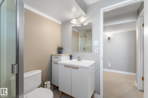 Bathroom featuring a white vanity with integrated sink, chrome faucet, and mirrored medicine cabinet - 14309 101 Avenue, Edmonton, AB 