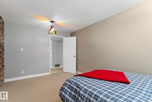 Carpeted room featuring a partial exposed brick wall and a decorative ceiling fixture - 14309 101 Avenue, Edmonton, AB 