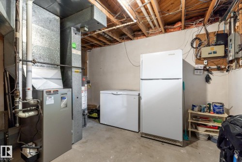 Utility area featuring a forced-air furnace, exposed ceiling joists, and concrete flooring - 14309 101 Avenue, Edmonton, AB 