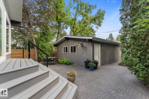 Composite deck with integrated steps, black metal railing, and a paver patio - 14309 101 Avenue, Edmonton, AB 