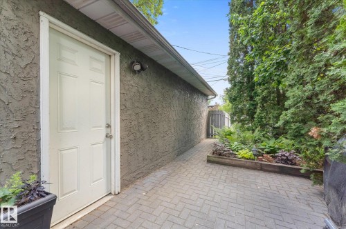Paved walkway featuring a herringbone pattern, bordered by a raised garden bed with diverse plantings - 14309 101 Avenue, Edmonton, AB 