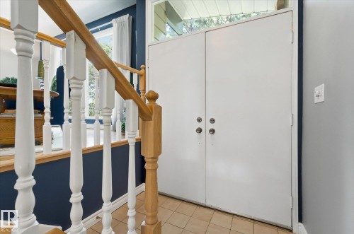 Double entry doors with transom window, tile flooring, and a staircase featuring a wood handrail and white balusters - 14309 101 Avenue, Edmonton, AB 