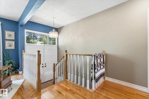 Hardwood flooring throughout this upper-level space, featuring a white baluster railing and wood handrail - 14309 101 Avenue, Edmonton, AB 