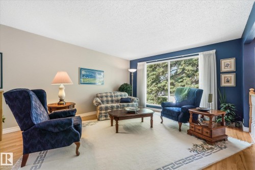 Spacious living area featuring large picture windows, wood-finish flooring, and crown molding - 14309 101 Avenue, Edmonton, AB 