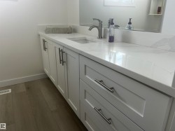 Contemporary vanity featuring white shaker-style cabinetry, a single integrated sink, a solid surface countertop with a matching backsplash, and brushed nickel hardware - 