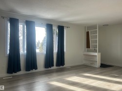 Spacious room featuring light wood-finish flooring and a series of four windows with white trim - 