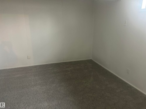 Carpeted room featuring white paneled walls and a baseboard trim - 14911 77 Street, Edmonton, AB 