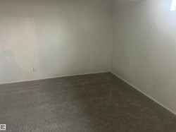 Carpeted room featuring white paneled walls and a baseboard trim - 