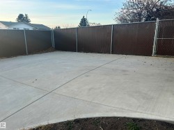 Concrete patio area featuring a chain-link fence with privacy slats - 