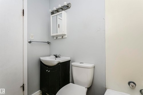 Compact bathroom featuring a white porcelain sink, dark wood-finish vanity, wall-mounted medicine cabinet, and a chrome towel bar - 10035 81 Avenue Nw, Edmonton, AB - Indoor Photo Showing Bathroom