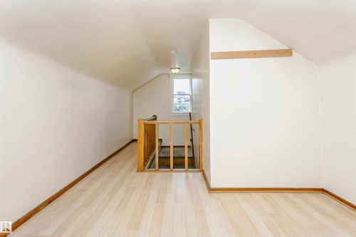Attic space featuring wood-finish flooring, white walls, and a window providing natural light - 10035 81 Avenue Nw, Edmonton, AB - Indoor Photo Showing Other Room
