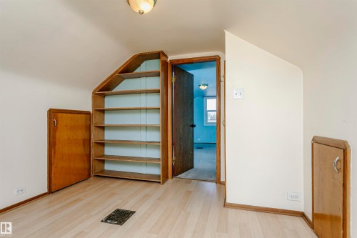 Light wood-finish flooring with an angled ceiling - 10035 81 Avenue Nw, Edmonton, AB - Indoor Photo Showing Other Room