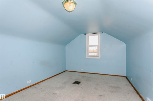 Attic space featuring sloped ceilings, a centered window, wall-to-wall carpeting, and wood baseboards - 10035 81 Avenue Nw, Edmonton, AB - Indoor Photo Showing Other Room