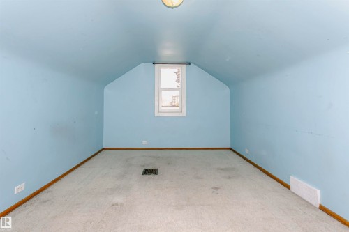 Room featuring sloped ceilings, light blue painted walls, neutral carpet, a single window, and a flush-mount ceiling light fixture - 10035 81 Avenue Nw, Edmonton, AB - Indoor Photo Showing Other Room